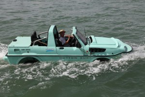 An amphibious car a.k.a. and amphicar, driving up the river